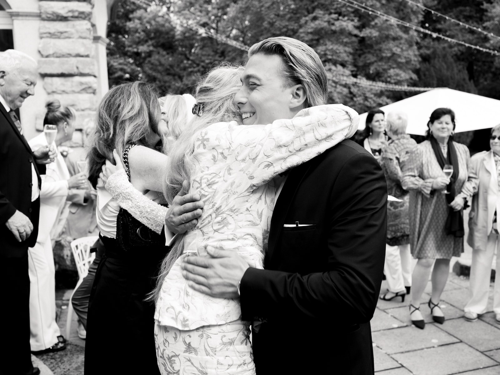 Guest embracing wedding couple after ceremony at Schloss Kartzow in black and white