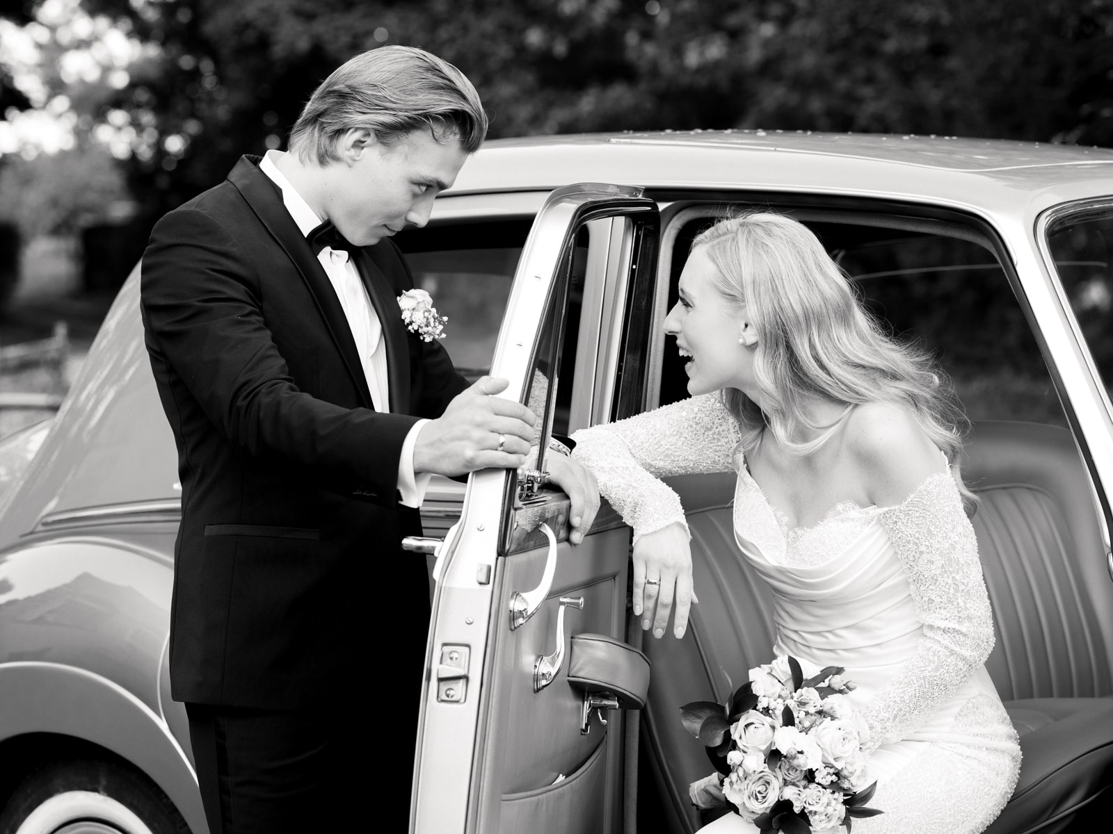 Groom helping bride get into vintage car at Schloss Kartzow castle wedding
