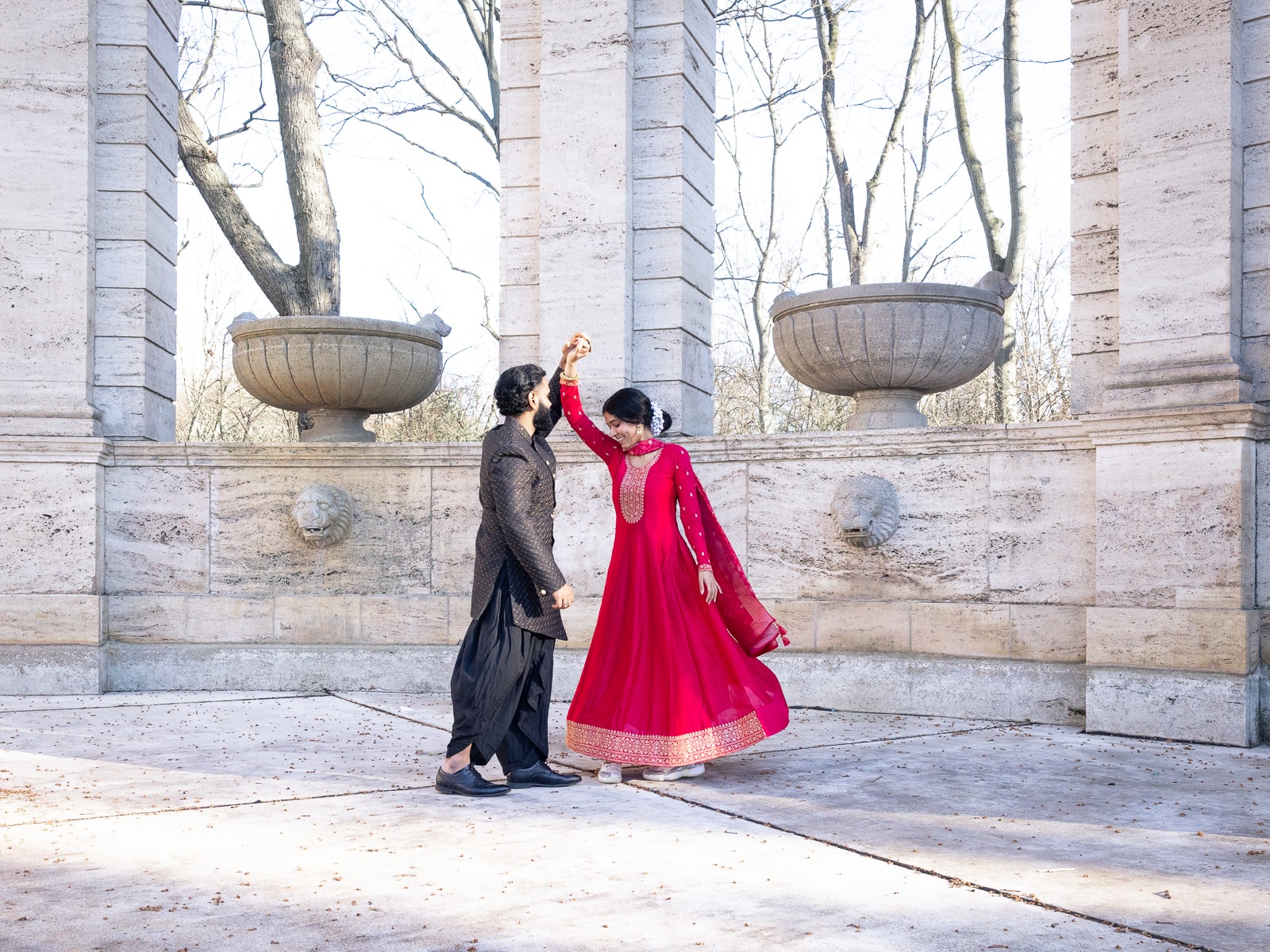 Dancing Indian bridal couple in sweeping movement in front of stone arcades