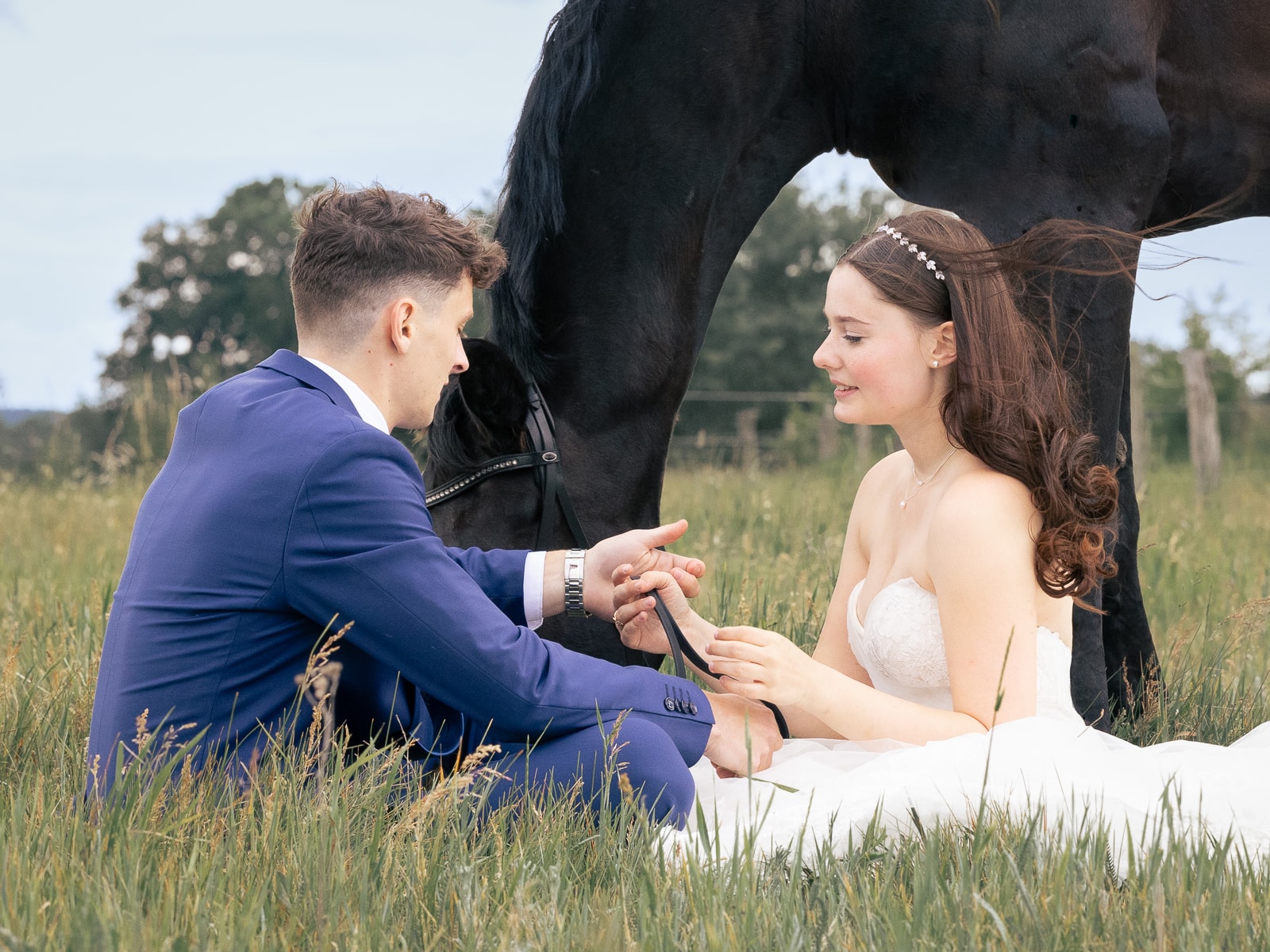 Groom showing bride engagement ring, black horse standing protectively over couple