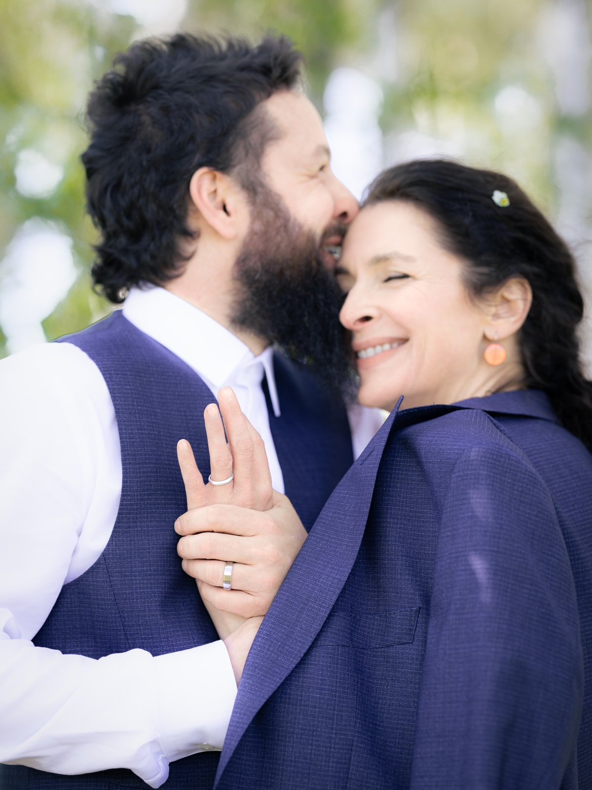 Groom and wedding guest in navy outfits smiling at each other