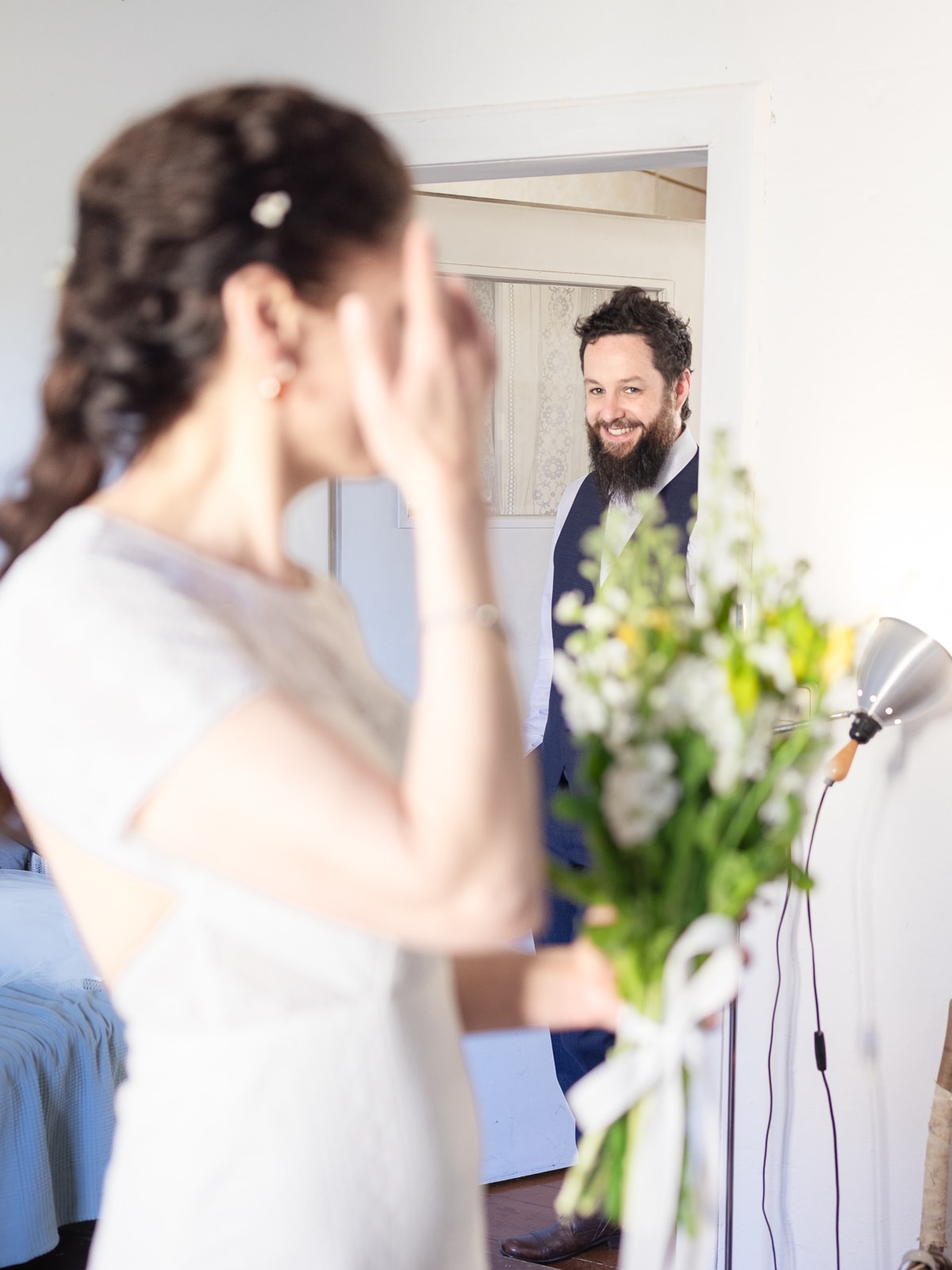 Bride looking over shoulder at smiling groom in doorway