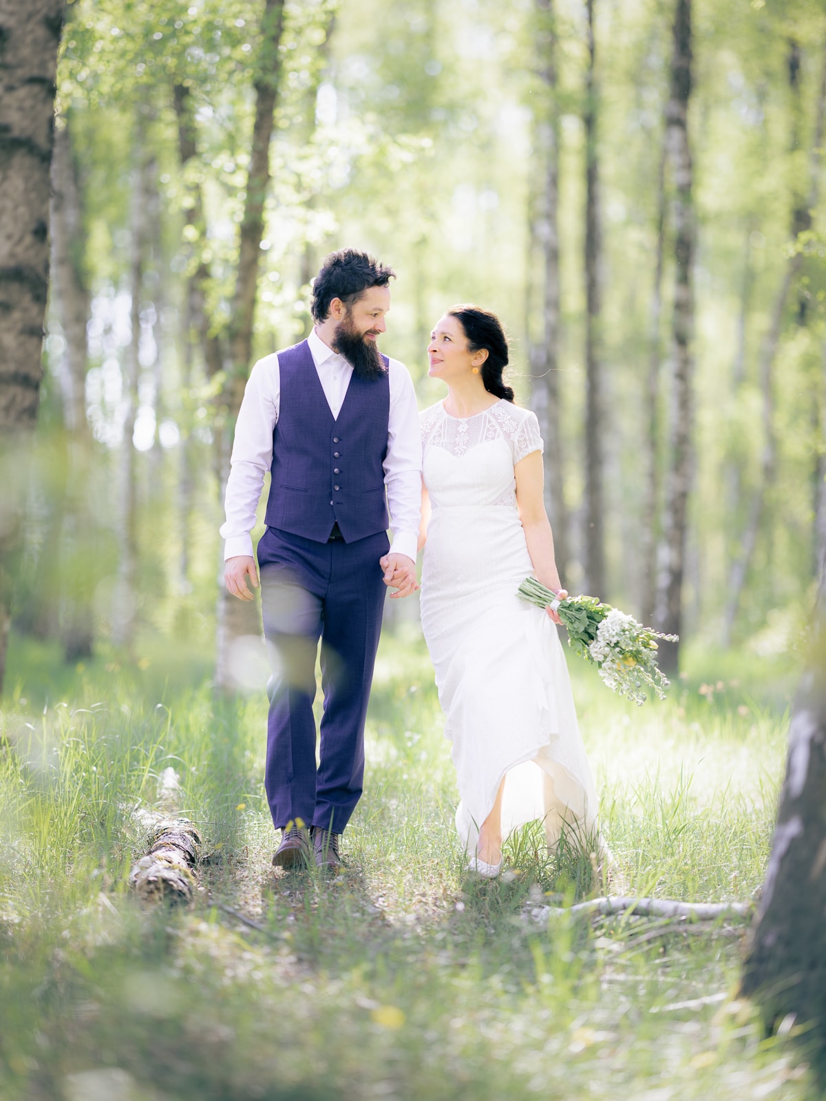 Laughing couple strolling through sunny birch forest