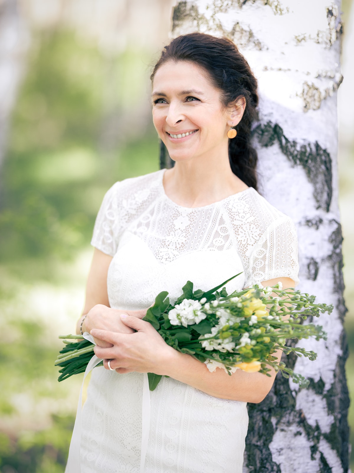 Bridal couple hand in hand in sun-drenched birch forest