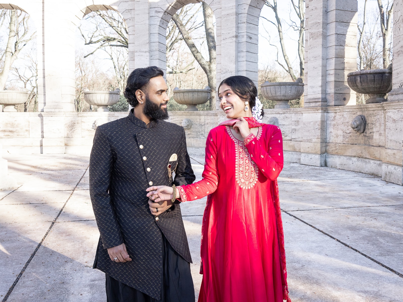 Laughing Indian bridal couple holding hands in joyful moment