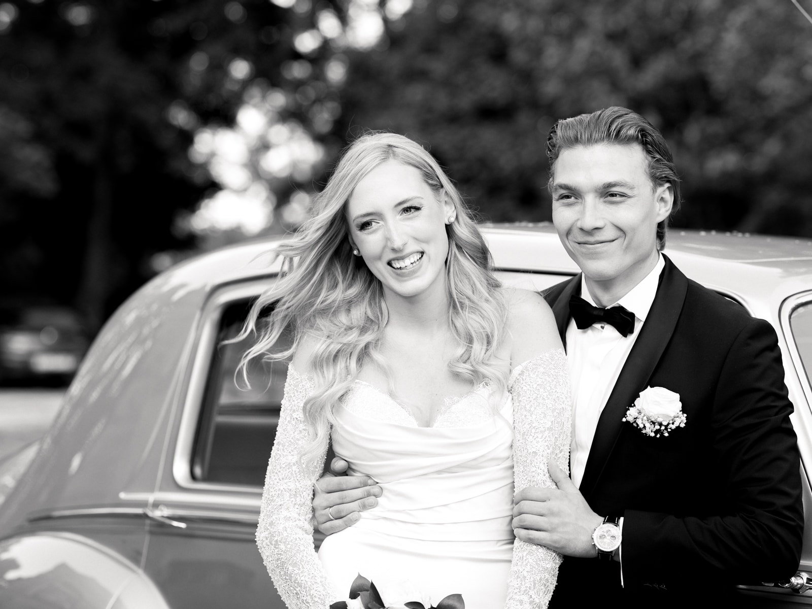 Happy wedding couple laughing in front of vintage wedding car at Schloss Kartzow castle wedding