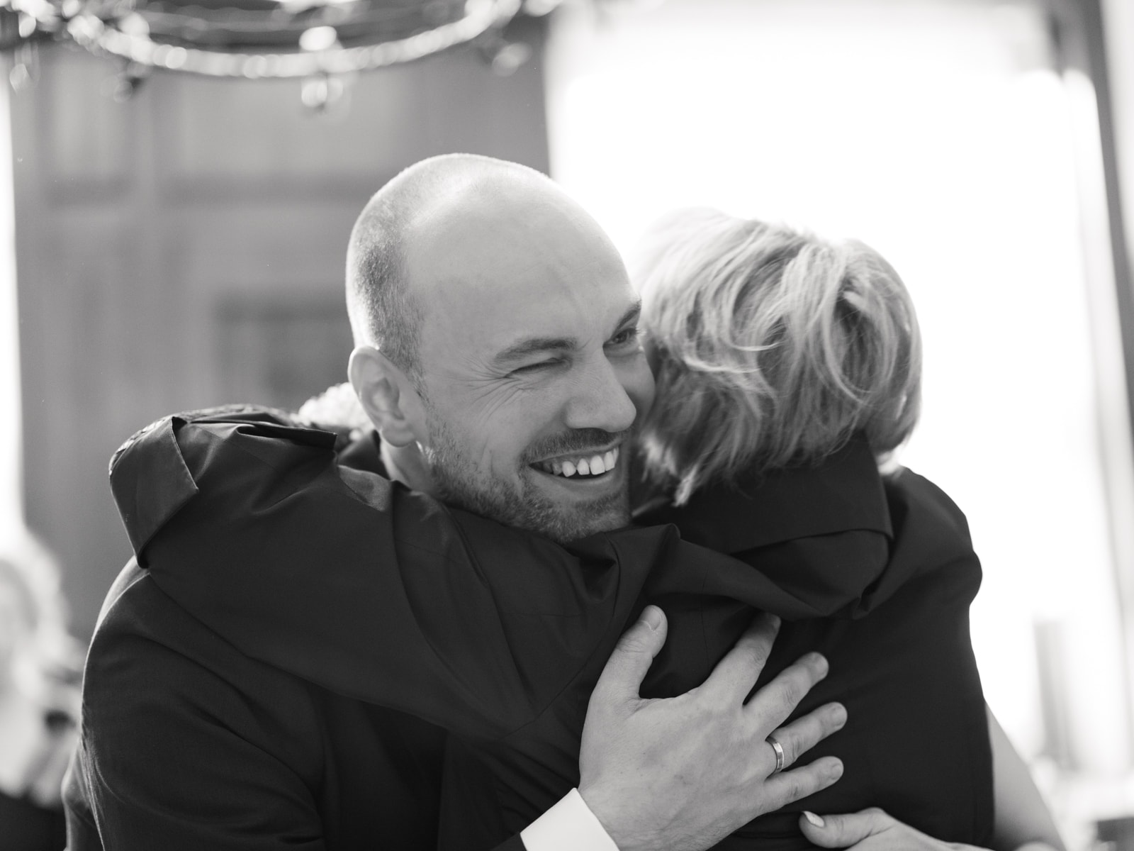 Groom warmly embracing a well-wisher after wedding