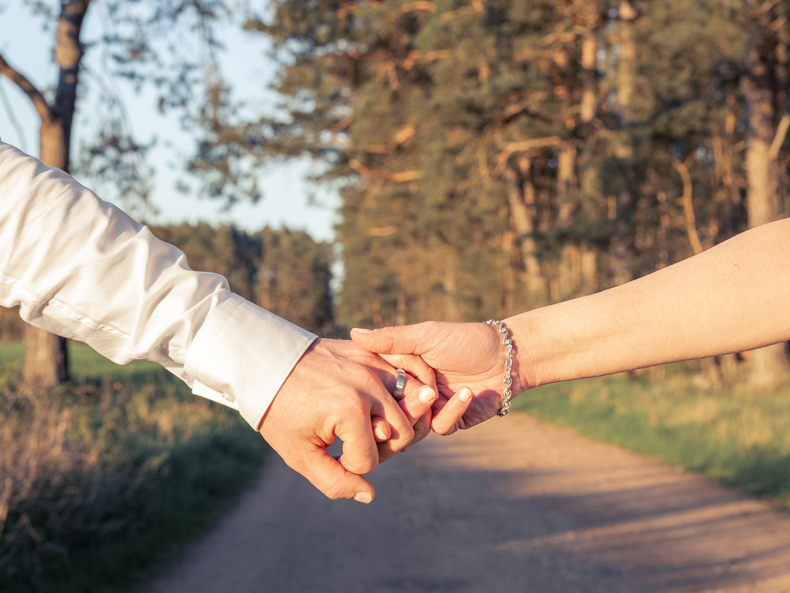 Couple's intertwined hands in warm evening light