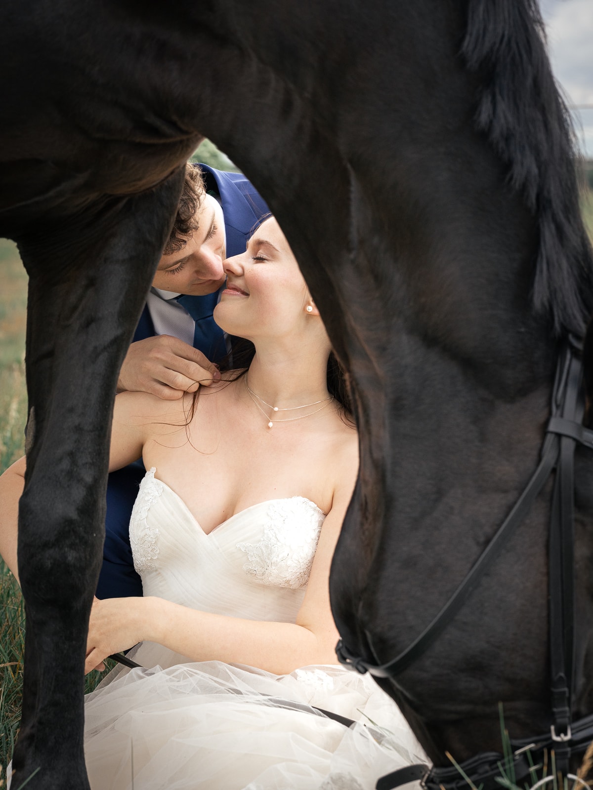 Intimate kiss of couple, framed by black horse body