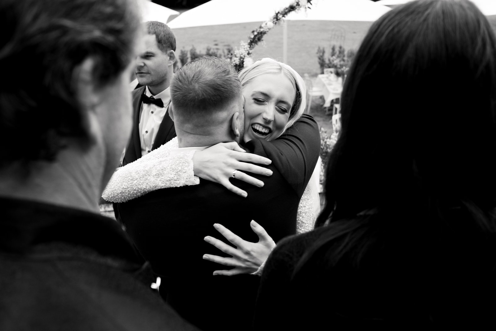 Bride laughing joyfully while hugging wedding guest after ceremony