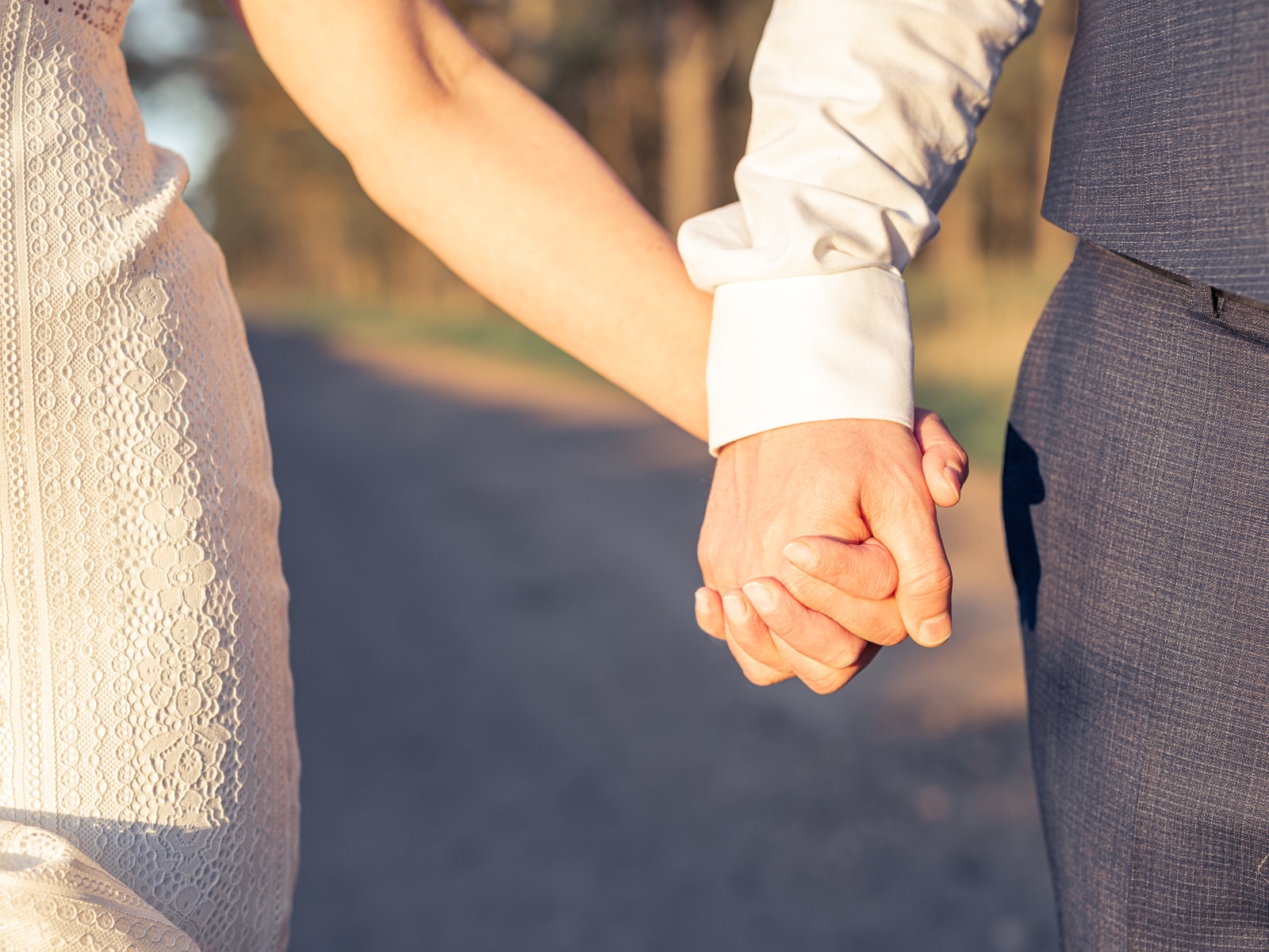 Detail shot of lace sleeves with couple's intertwined hands