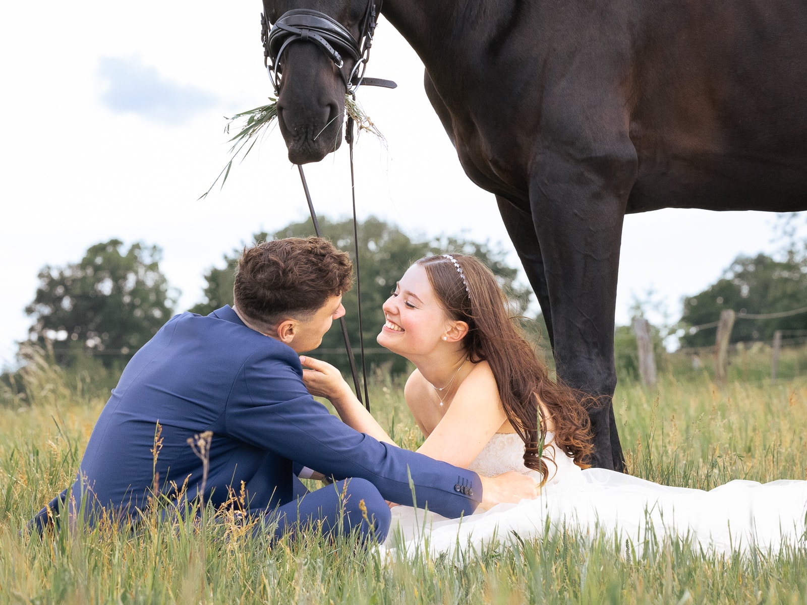 Groom tenderly kissing bride's forehead under black horse's head
