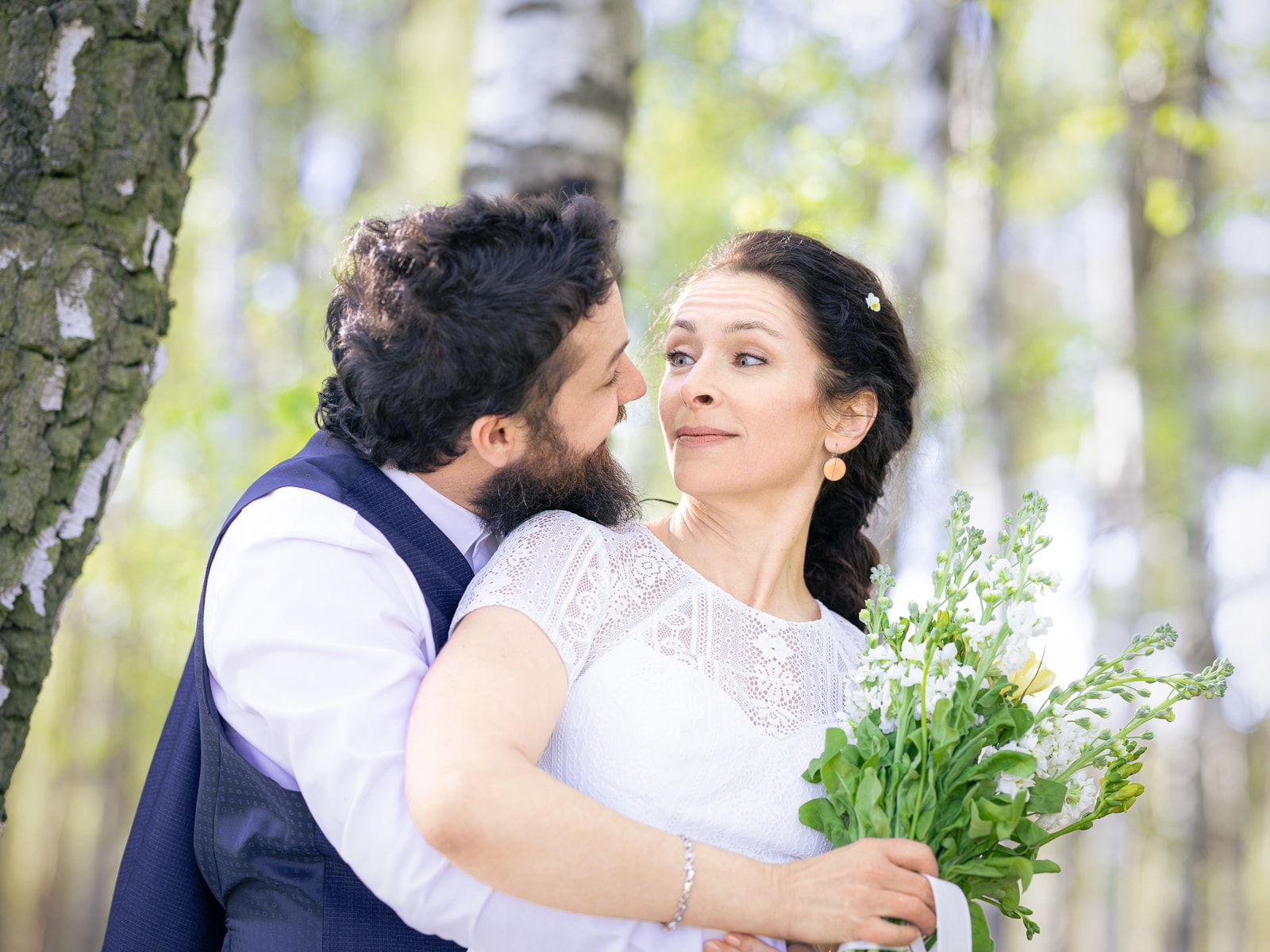 Playful bride making funny face in groom's embrace