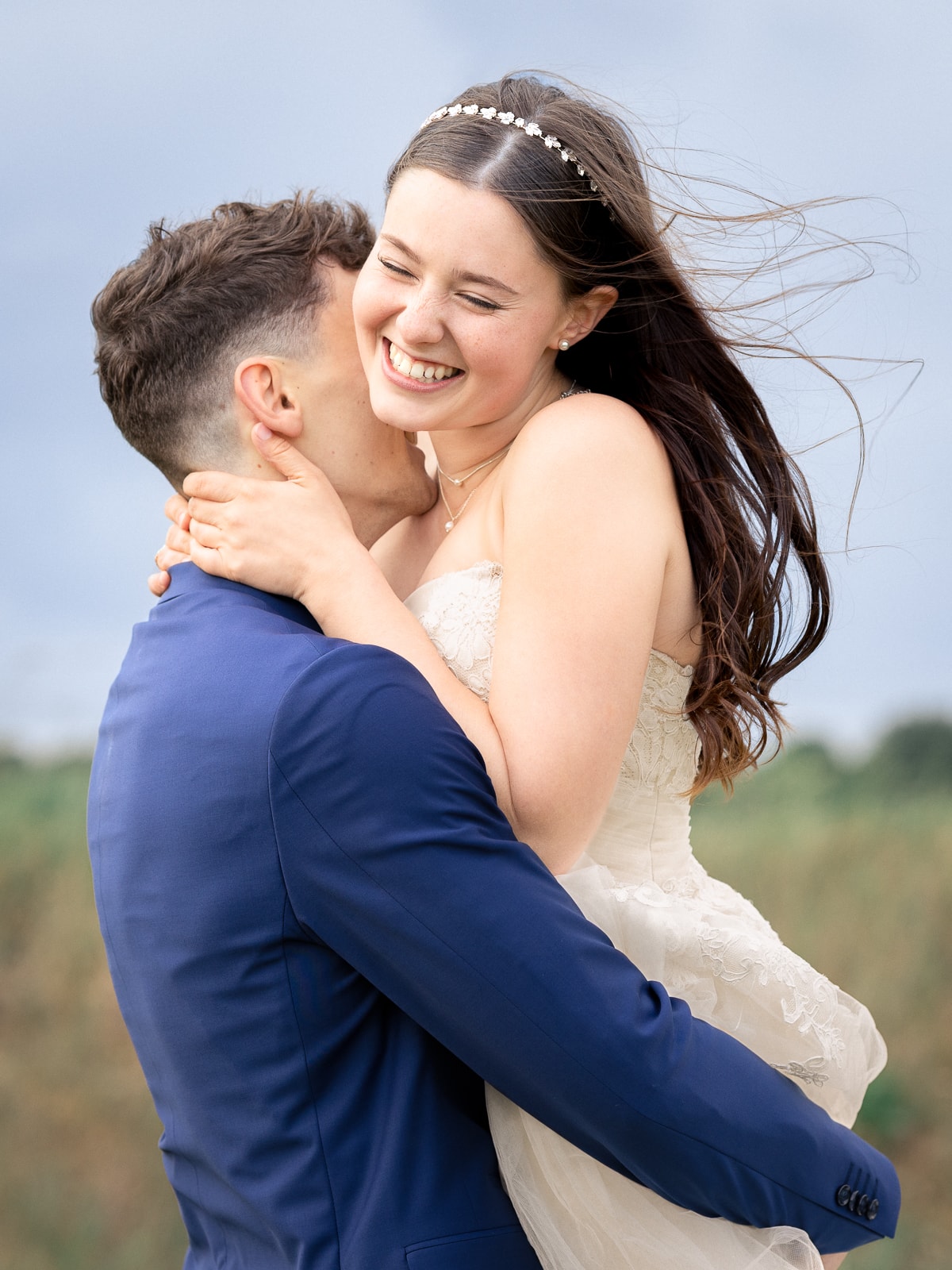 Overjoyed bride with flowing hair embracing groom from behind
