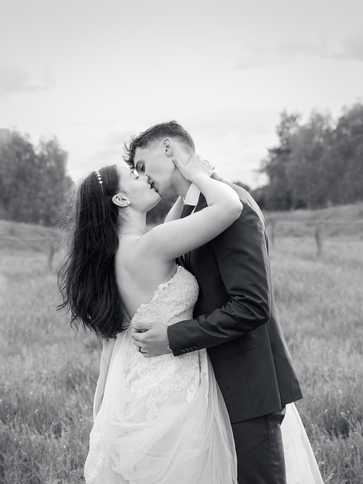 Intimate kiss of couple on field path in classic black and white