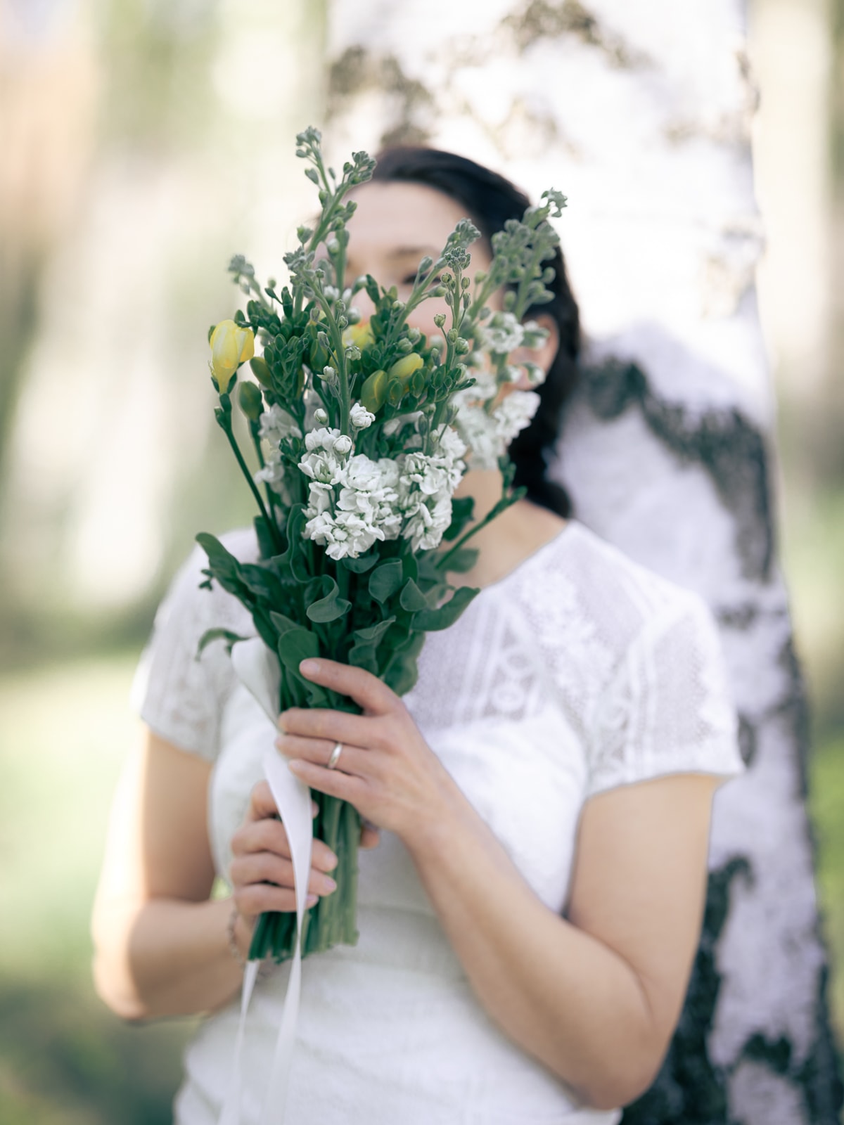 Groom tenderly embracing bride from behind in birch forest