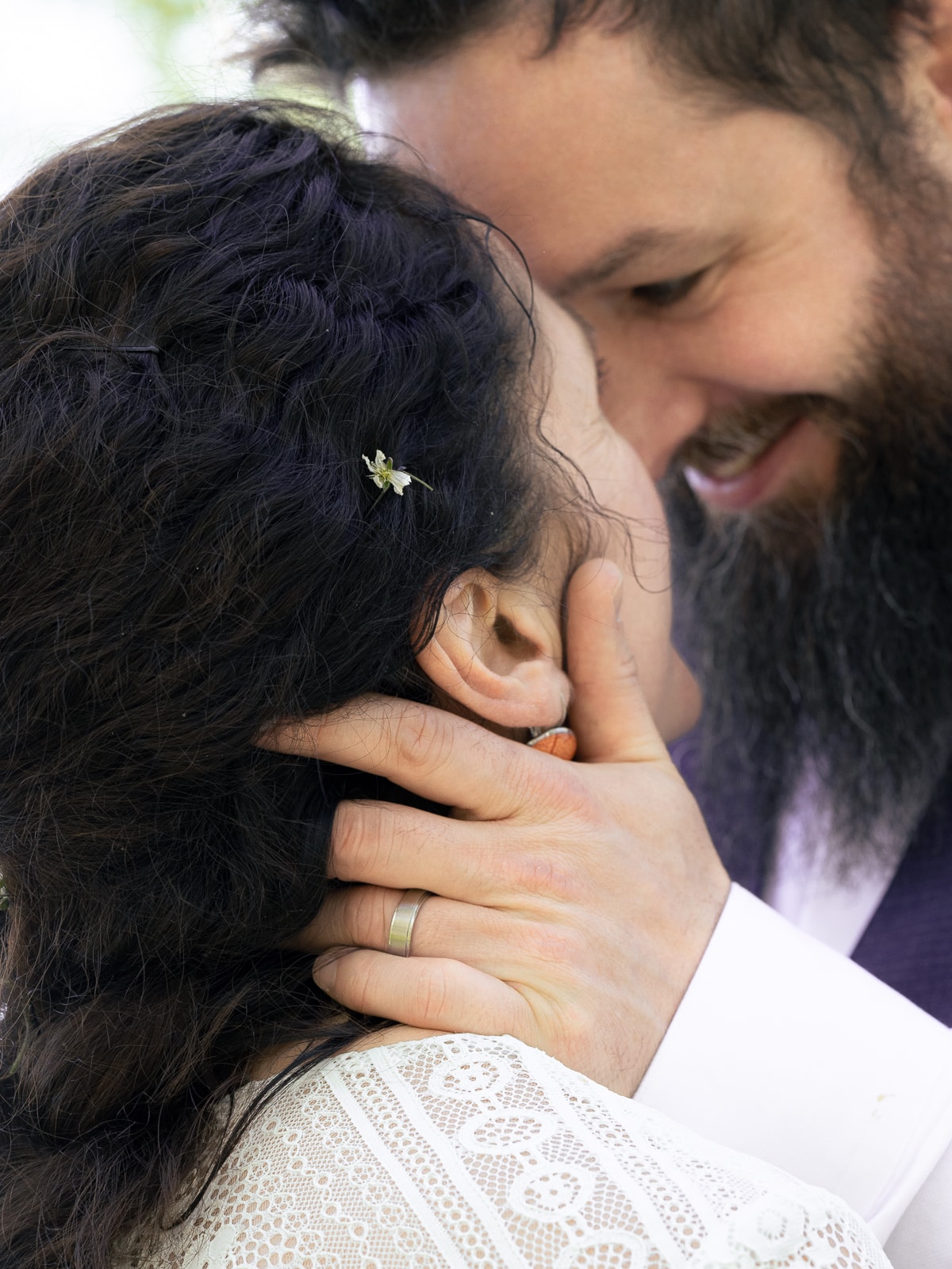 Groom's hand on bride's head with flower hair accessory