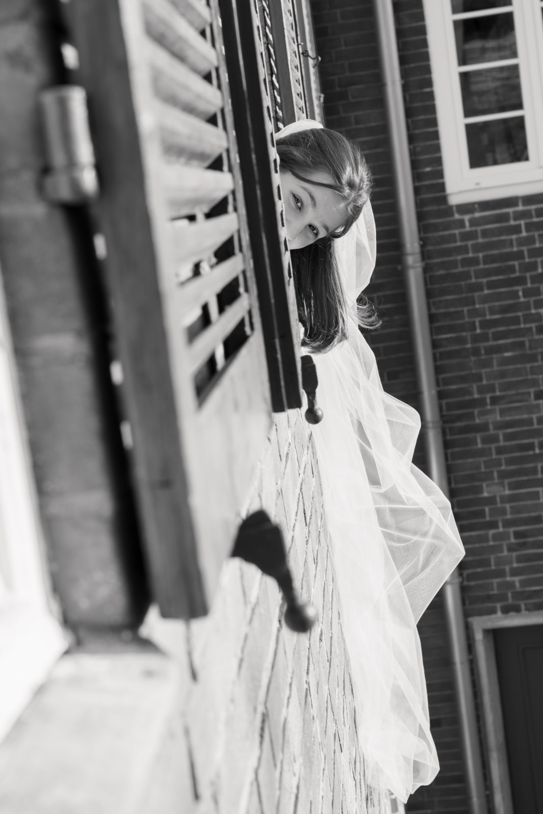 Bride peeking playfully around corner in urban wedding photography