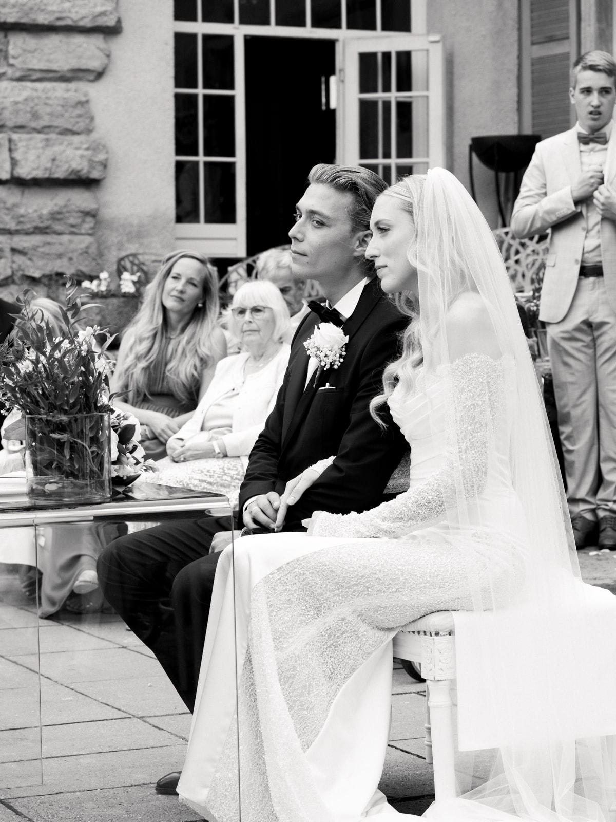 Wedding couple seated during wedding ceremony at Schloss Kartzow with guests in background