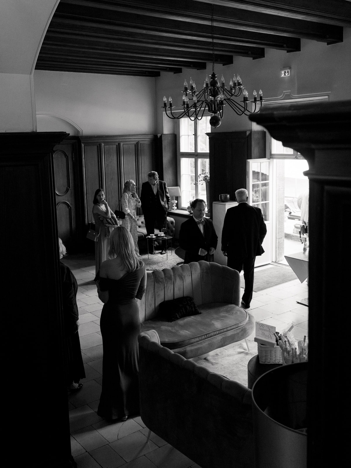 Wedding guests in elegant castle hall with chandelier and antique furniture, wedding photography Schloss Kartzow