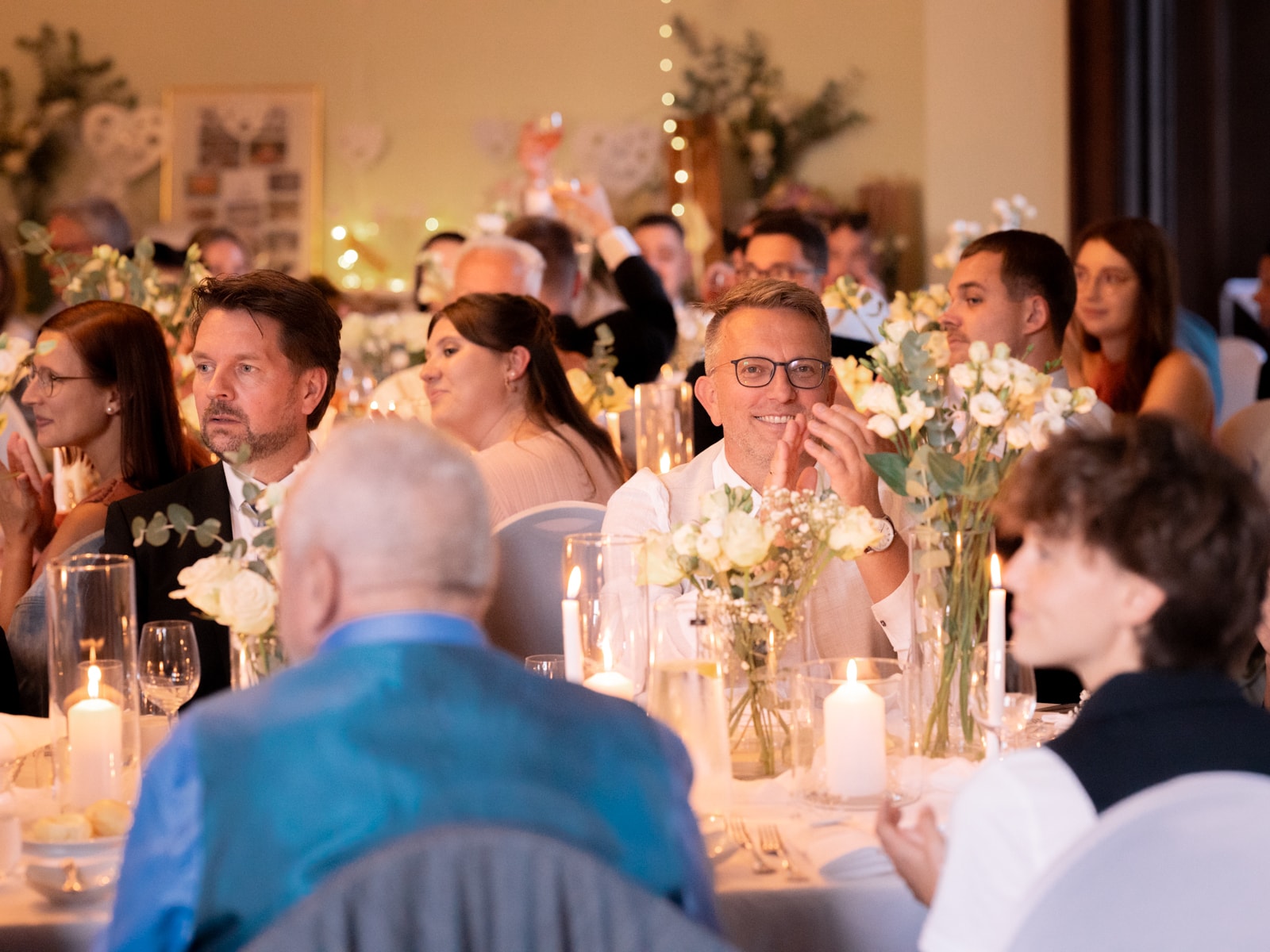 Smiling wedding guests at festively decorated tables with candles - Schloss Kartzow celebration