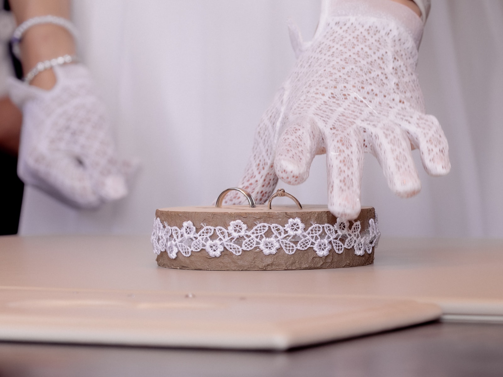 Golden wedding rings on rustic wood with lace ribbon