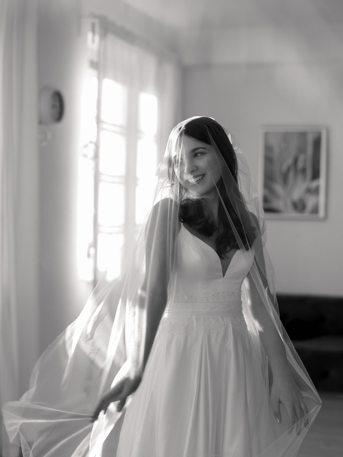Smiling bride with veil in window light in classic black and white