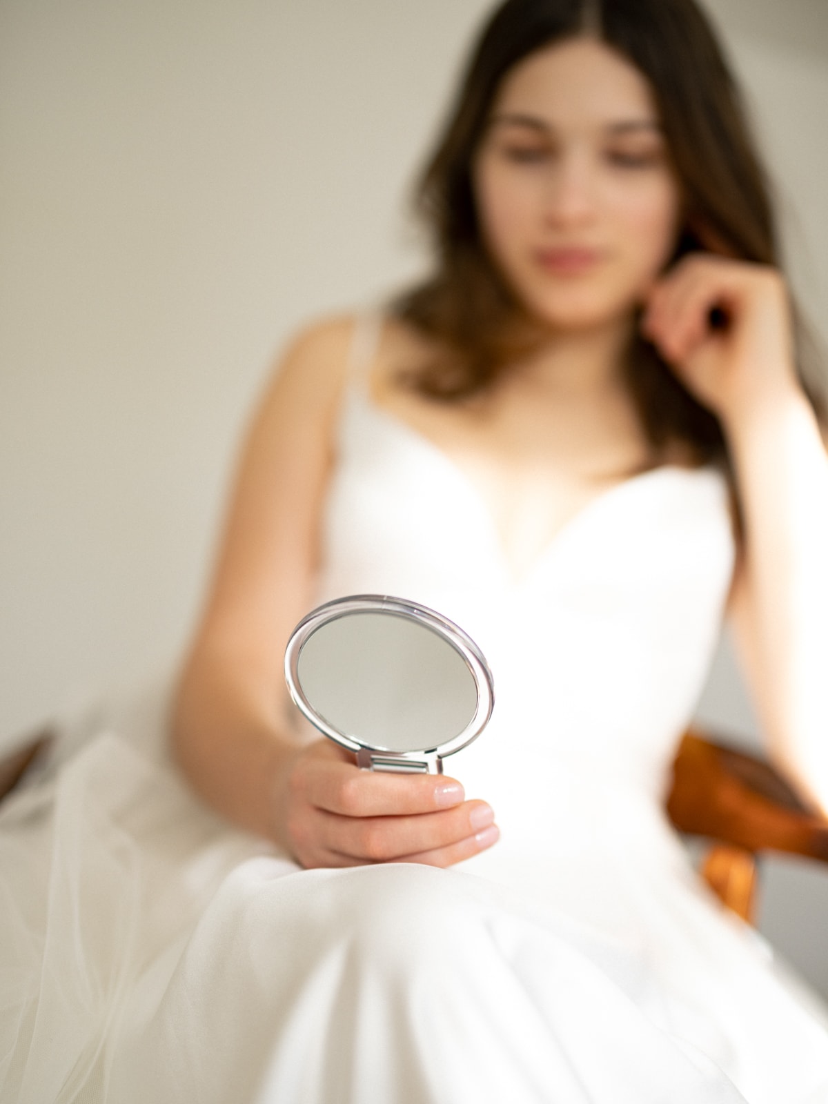 Bride holding hand mirror during wedding preparations