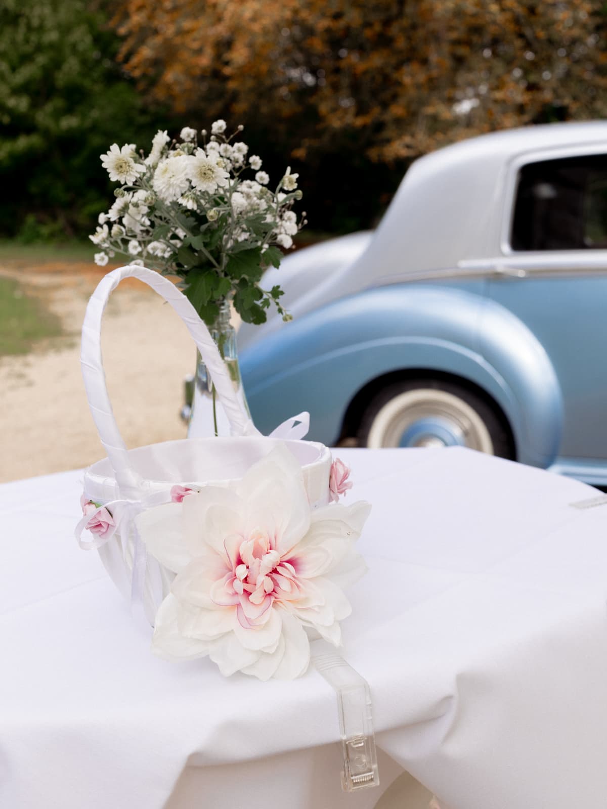 Weißer Blumenkorb mit rosa Dahlien und weißen Rosen vor vintage Hochzeitsauto bei Schloss Kartzow