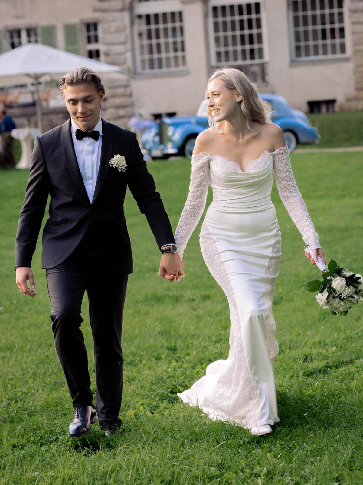 Brautpaar geht Hand in Hand durch Schlosspark Kartzow bei Sommerhochzeit