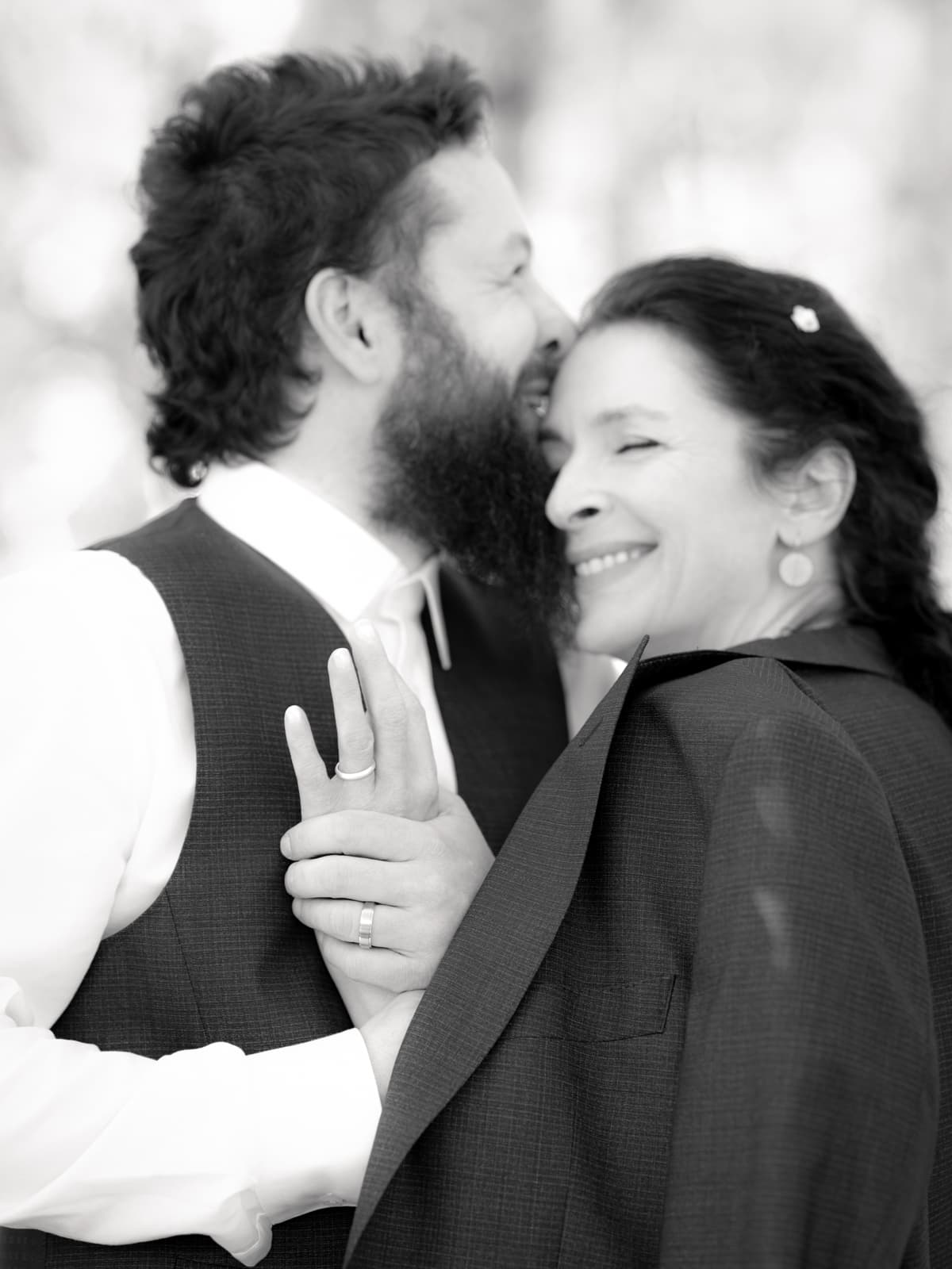 Bräutigam und Hochzeitsgast in marineblauen Outfits lächeln sich an