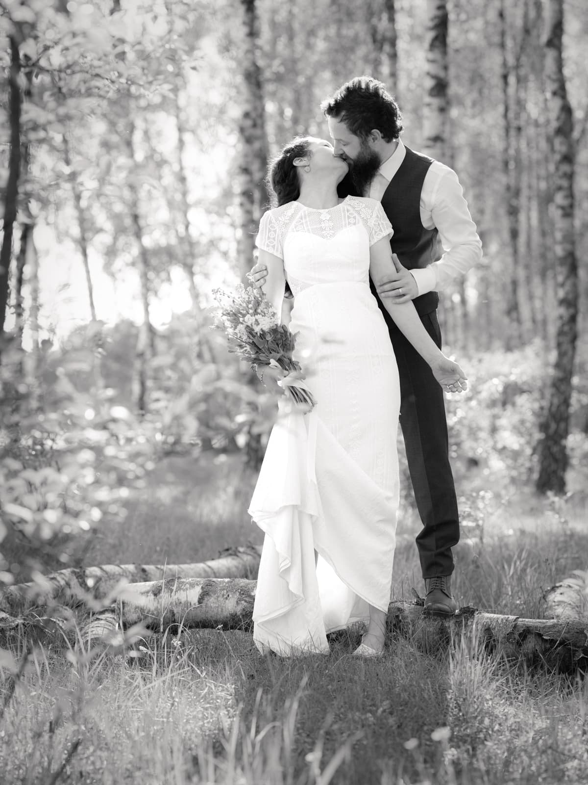 Brautpaar küsst sich zärtlich im sonnigen Birkenwald
