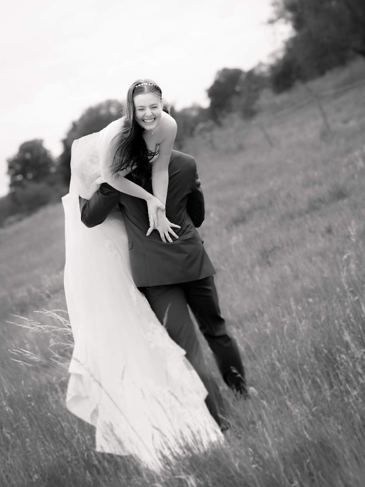 Fröhliches Brautpaar in spielerischer Bewegung auf ländlichem Weg