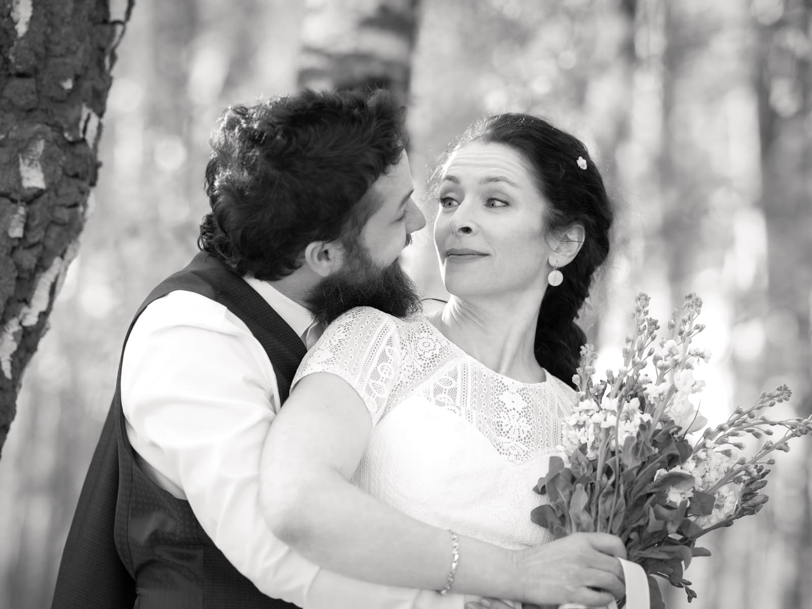 Verspielte Braut mit lustiger Grimasse in Umarmung des Bräutigams